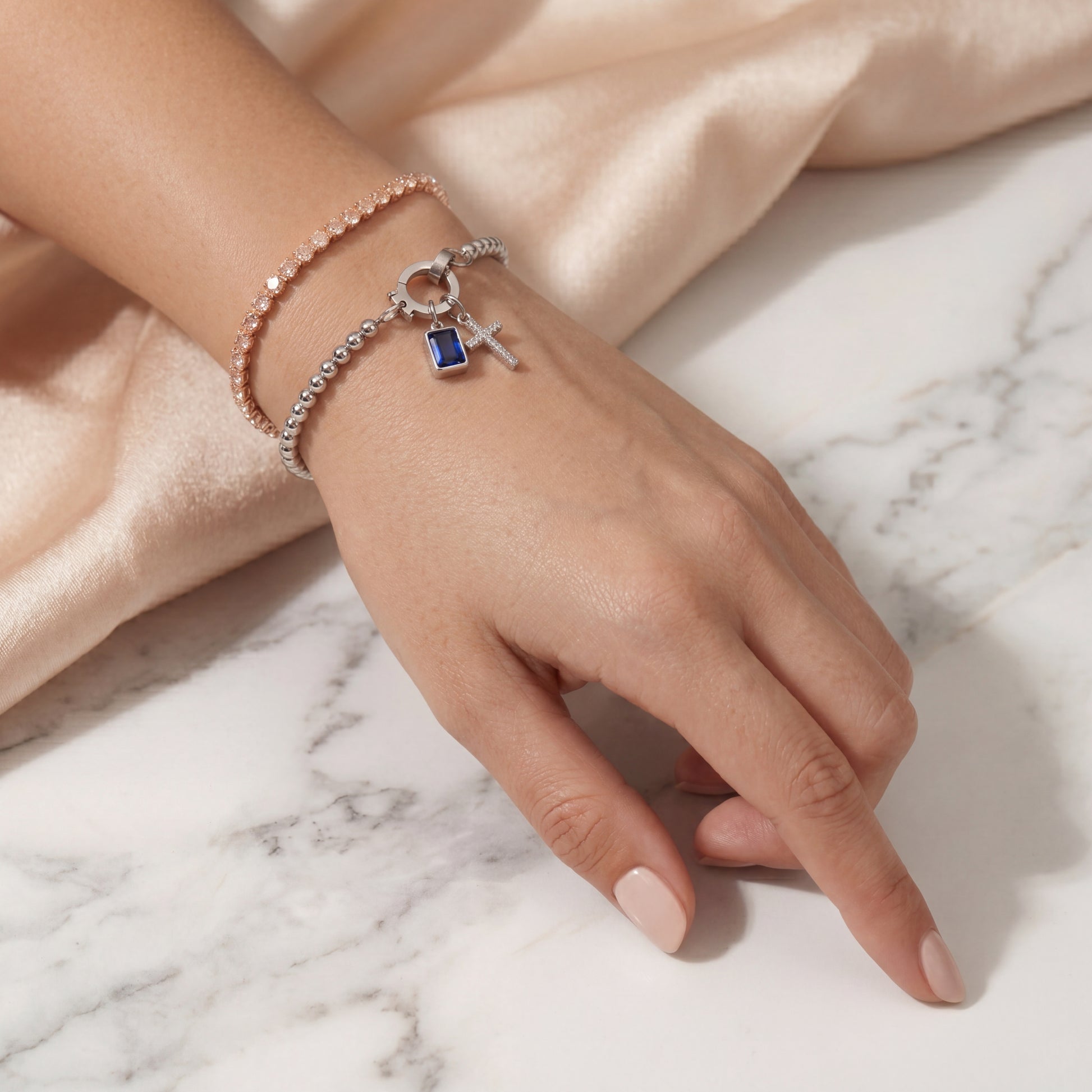 Pulsera de Veska con dije de cruz y piedra natal, joyería elegante en plata con detalles religiosos y piedras brillantes.