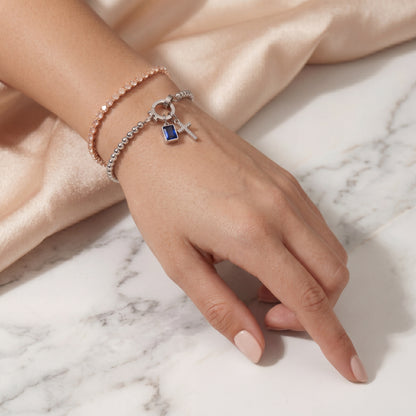 Pulsera de Veska con dije de cruz y piedra natal, joyería elegante en plata con detalles religiosos y piedras brillantes.