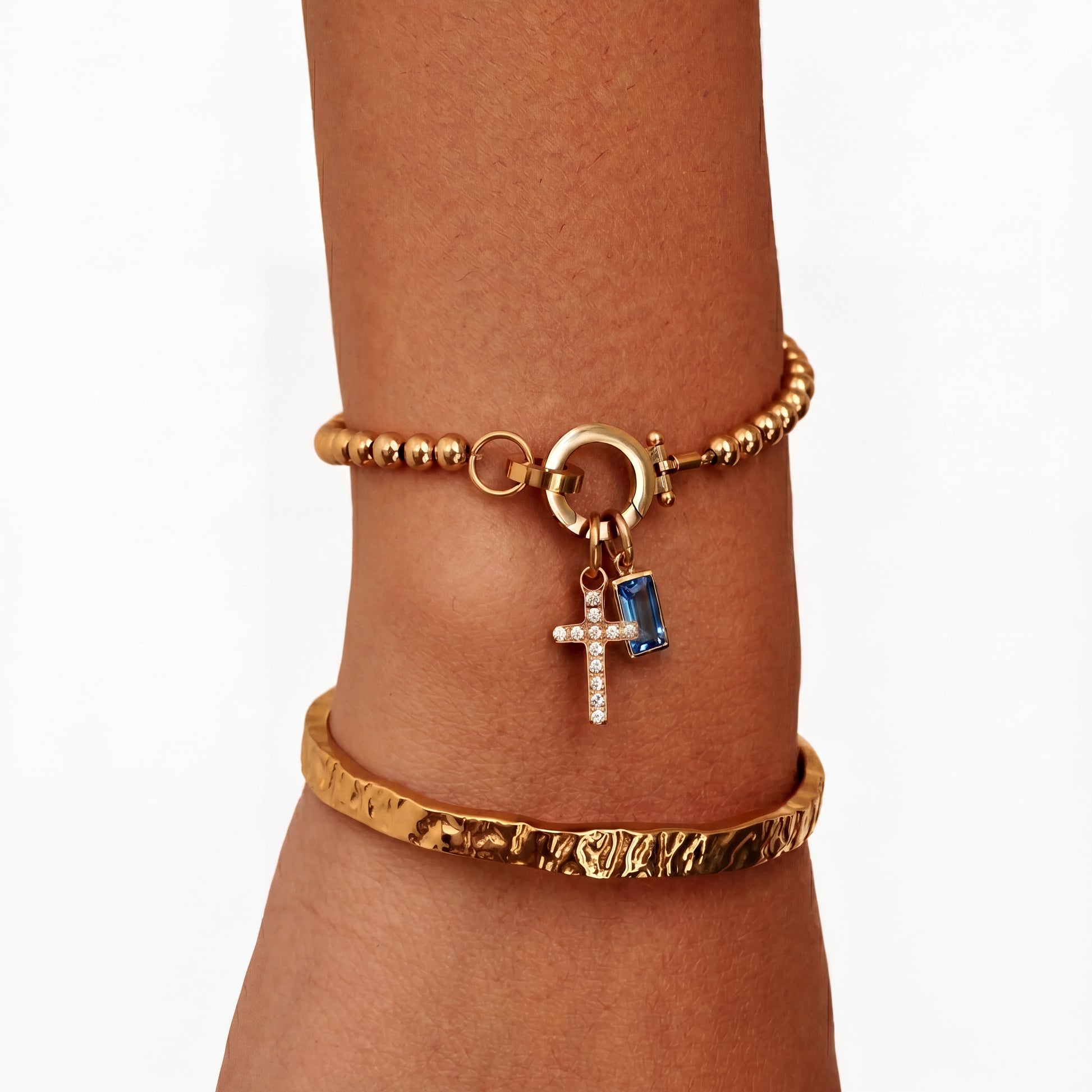 Pulsera de Veska con dije de cruz y piedra natal, diseñada en plata con detalles elegantes y simbólicos.