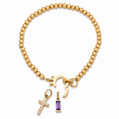 Pulsera de Veska con dije de cruz y piedra natal, joya elegante con detalles religiosos y piedra preciosa en la pieza.