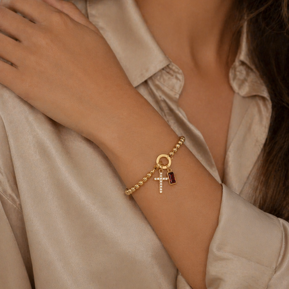 Pulsera Veska con dije de cruz y piedra natal, joyería en plata con detalles religiosos y piedra semipreciosa.